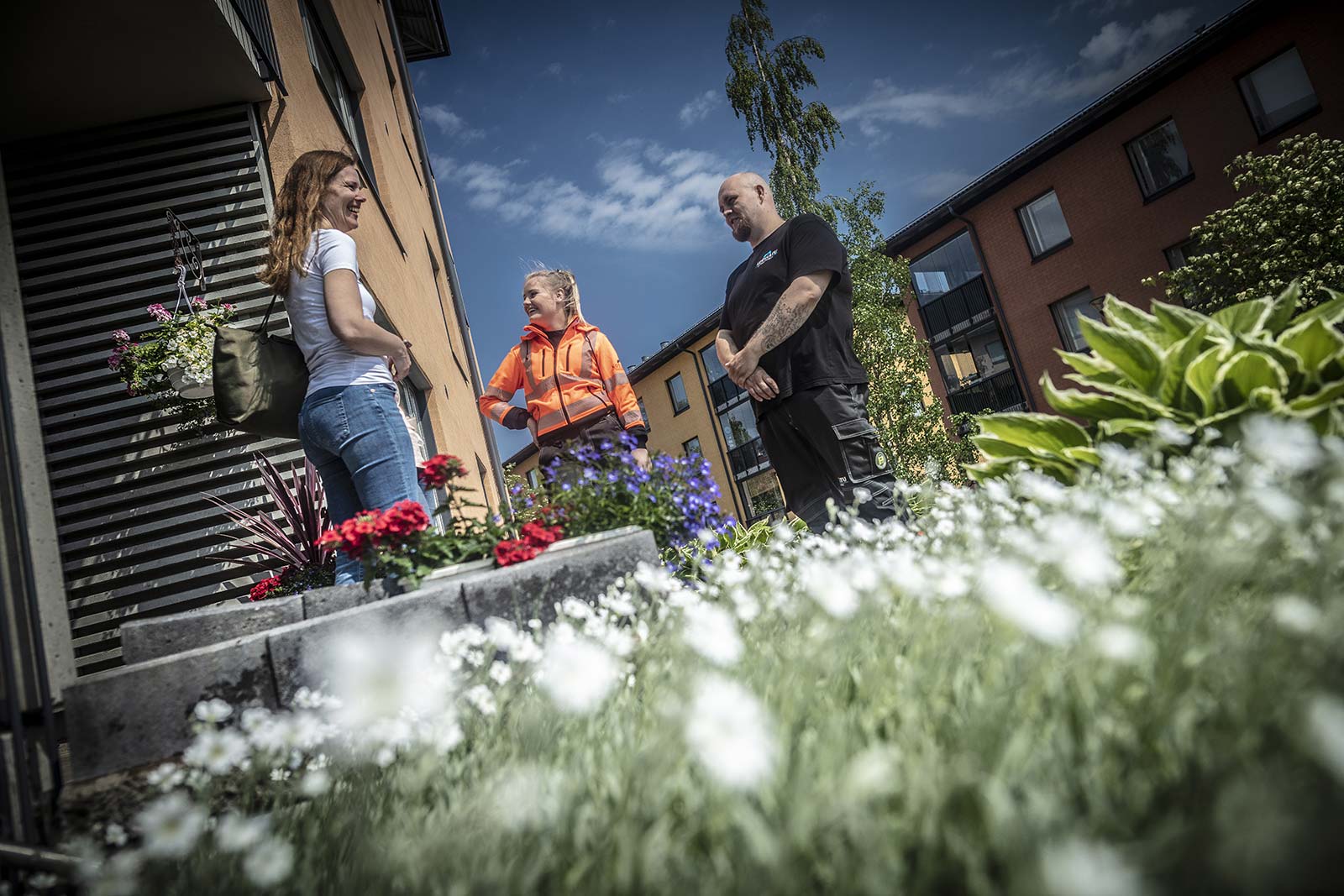 Ihmiset kokoontuneet kerrostaloyhtiön pihalle